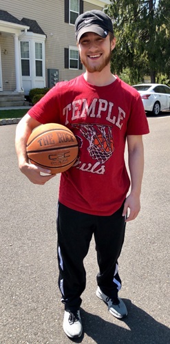 Former patient Alec Berenbaum standing in driveway and holding basketball